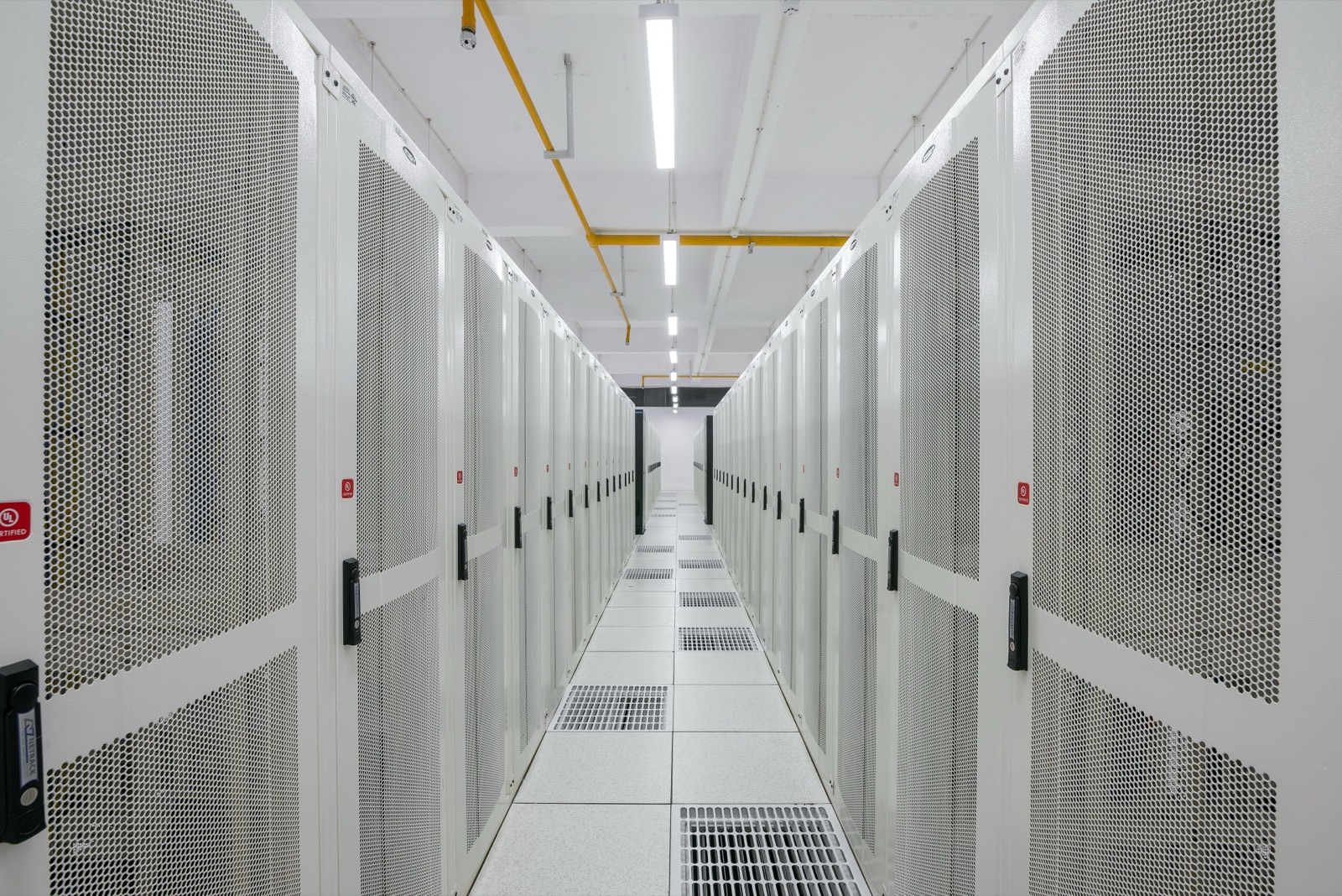 A data hall with rows of enclosed server racks and overhead cable trays